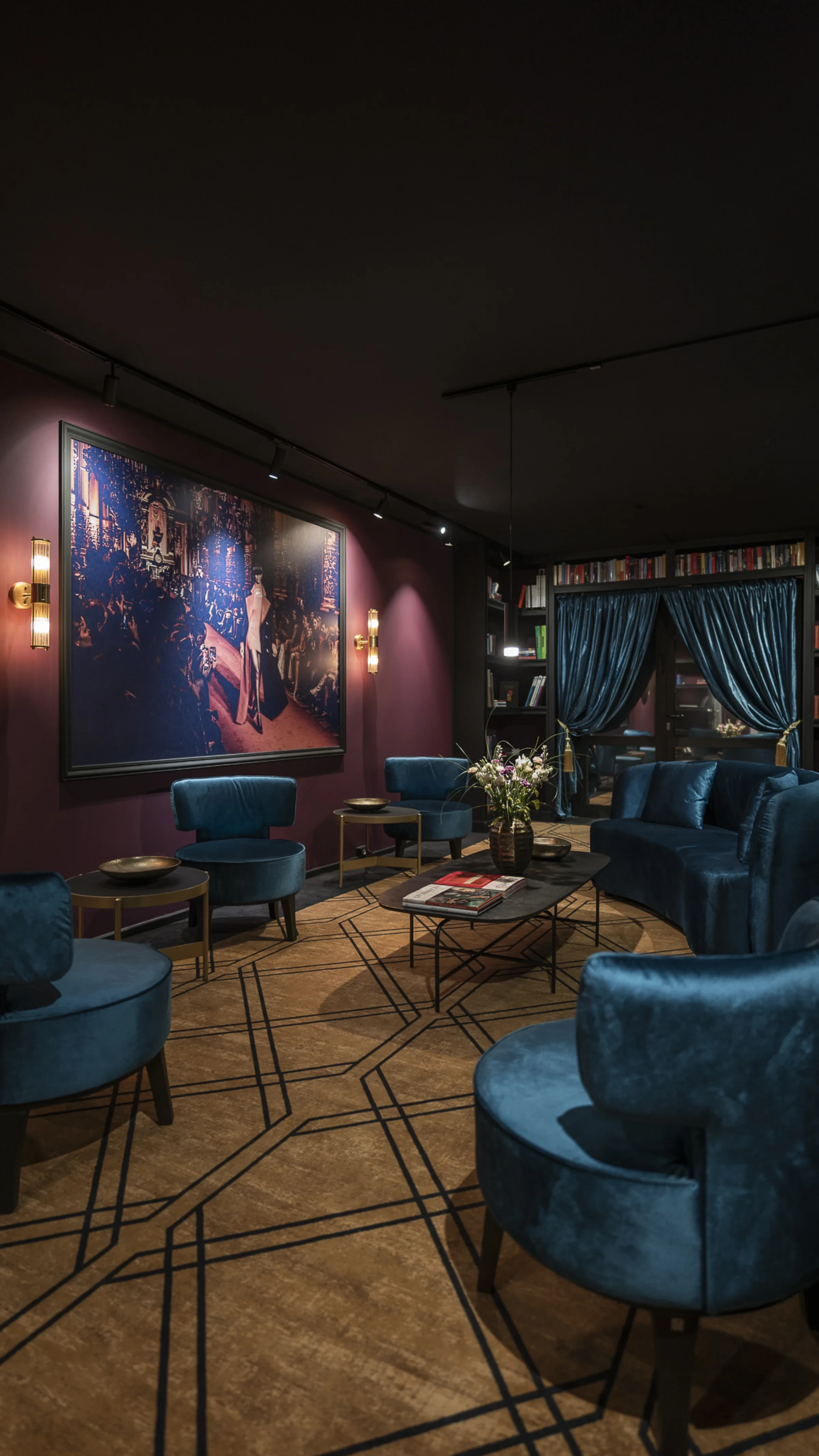 Leipzig Suites Welcomelounge mit Bibliothek und blauem Samtvorhang — Rückzugsort für Langzeitgäste