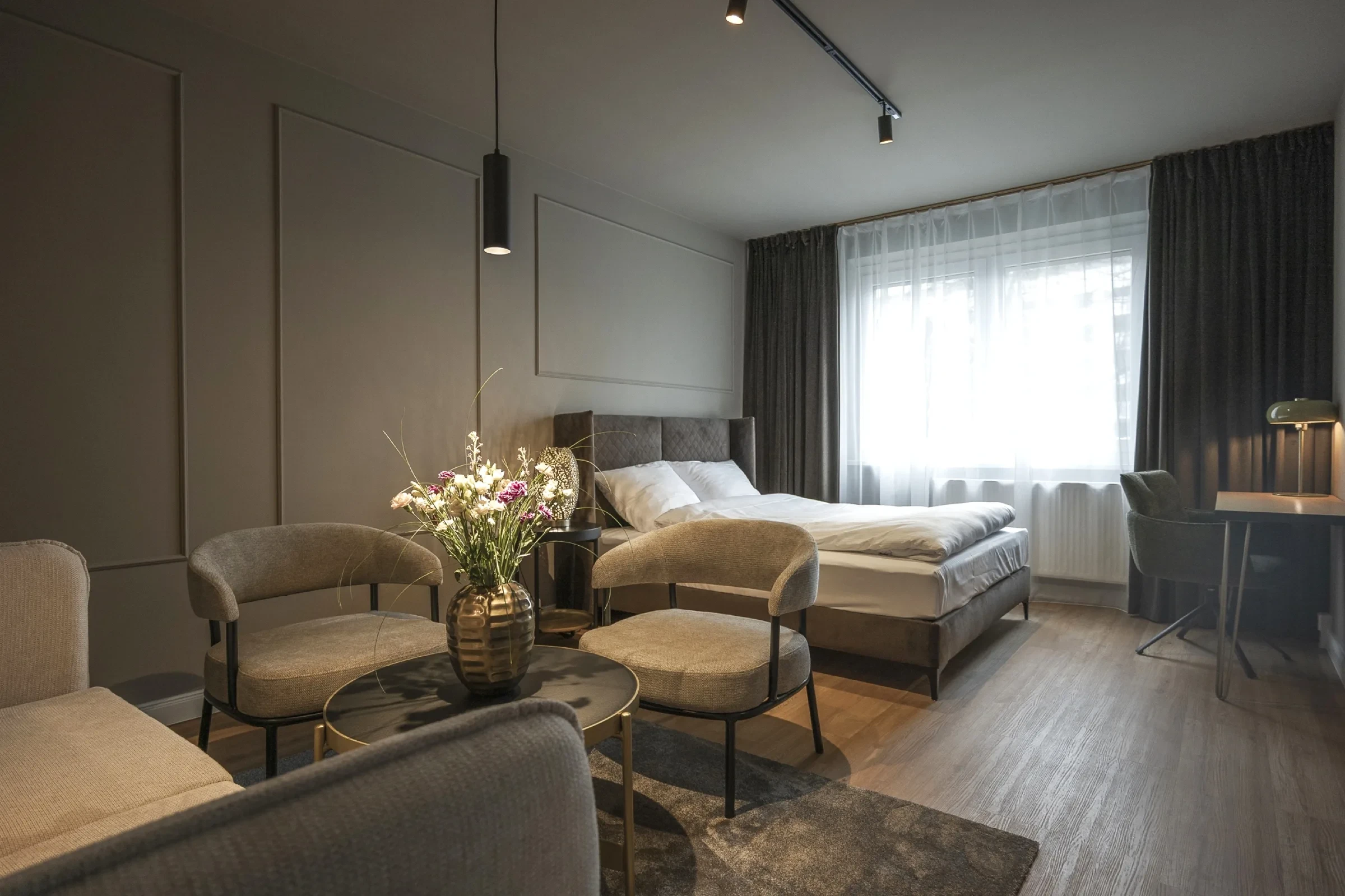 Junior Suite mit Balkon Leipzig — Schlafzimmer mit Sitzecke und Schreibtisch bei Tageslicht